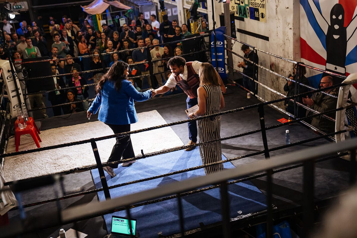 Eerste 2 debatleden schudden elkaar de hand in de boksring met Marjolein Lanzing als de scheidsrechter